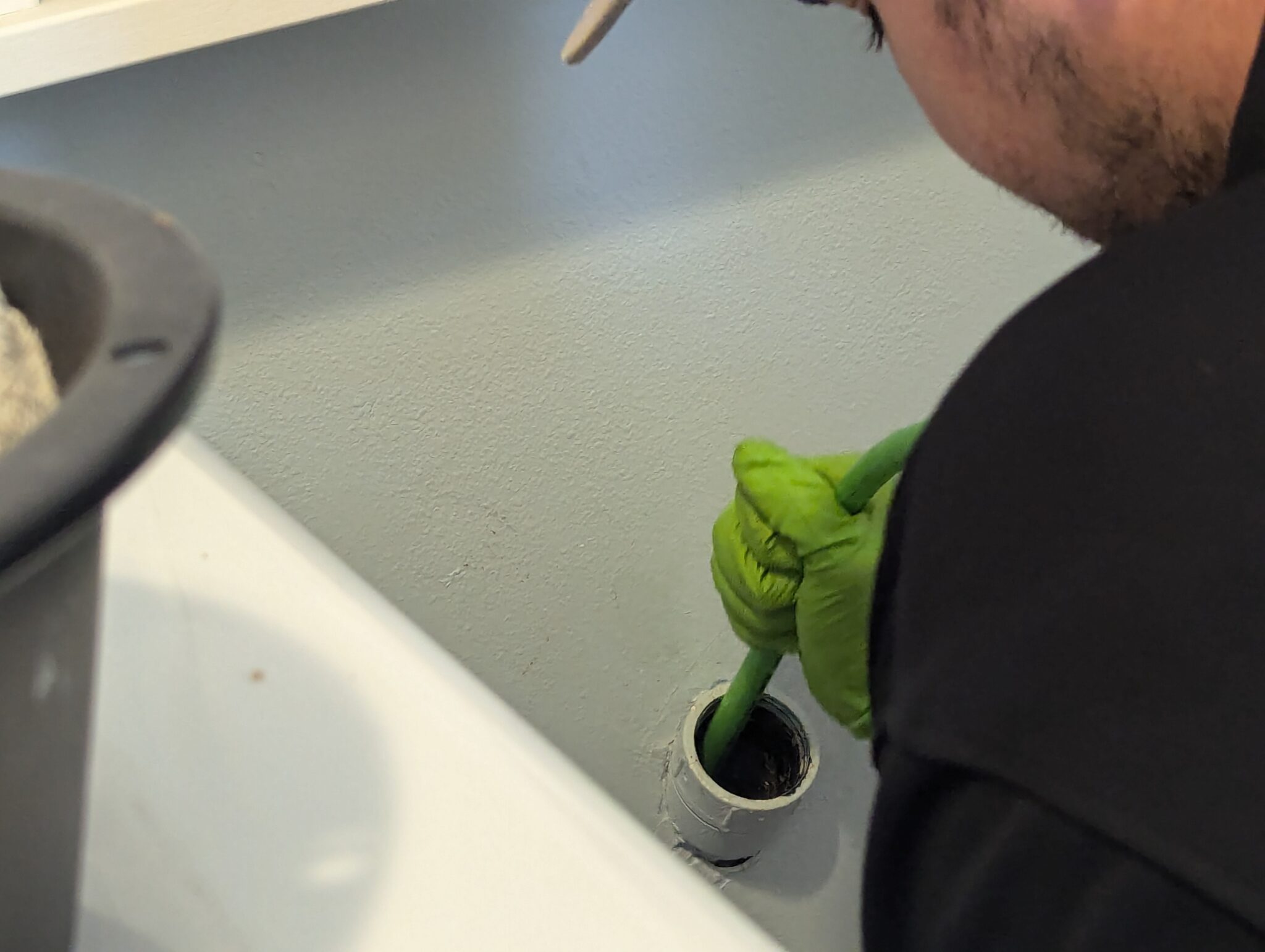 Plumber clearing a clogged sink drain with a drain snake in Burlington, WA